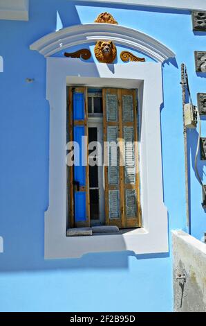 Traditionelles Landhausfenster mit hölzernen Fensterläden an einer hellblauen Putzwand auf der Insel Karpathos, Dodekanes Griechenland. Stockfoto