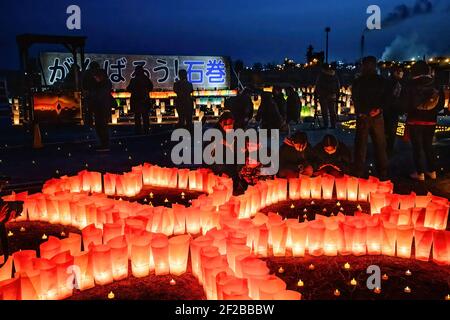 Ishinomaki, Japan. März 2021, 11th. Die Menschen zünden in der Nacht Kerzen an als Symbol des Lichts in der Dunkelheit, um an die vor 10 Jahren Getöteten vor der Tafel "Ganbare Ishinomaki" zu erinnern. Japan ist seit 10 Jahren ein massives Erdbeben, Tsunami und Atomkrise, die den Nordosten Japans hart getroffen haben. Kredit: SOPA Images Limited/Alamy Live Nachrichten Stockfoto