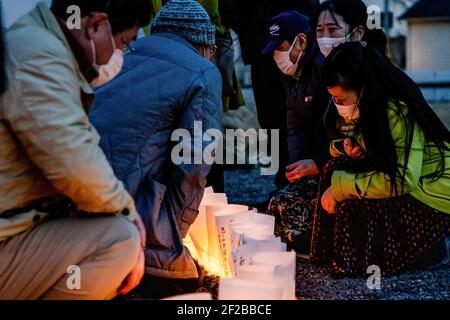 Ishinomaki, Japan. März 2021, 11th. Die Menschen zünden in der Nacht Kerzen an als Symbol des Lichts in der Dunkelheit, um an die vor 10 Jahren Getöteten vor der Tafel "Ganbare Ishinomaki" zu erinnern. Japan ist seit 10 Jahren ein massives Erdbeben, Tsunami und Atomkrise, die den Nordosten Japans hart getroffen haben. Kredit: SOPA Images Limited/Alamy Live Nachrichten Stockfoto