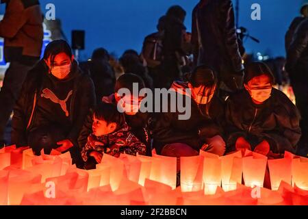 Ishinomaki, Japan. März 2021, 11th. Die Menschen zünden in der Nacht Kerzen an als Symbol des Lichts in der Dunkelheit, um an die vor 10 Jahren Getöteten vor der Tafel "Ganbare Ishinomaki" zu erinnern. Japan ist seit 10 Jahren ein massives Erdbeben, Tsunami und Atomkrise, die den Nordosten Japans hart getroffen haben. Kredit: SOPA Images Limited/Alamy Live Nachrichten Stockfoto