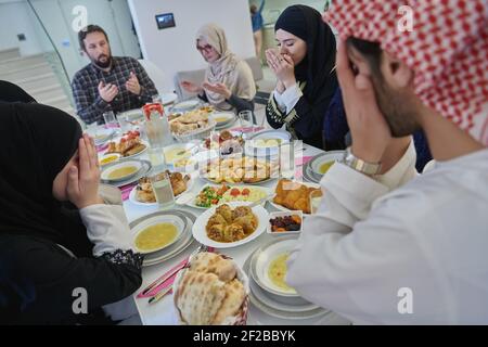Muslimische Familie macht iftar dua Fasten während Ramadan zu brechen. Stockfoto