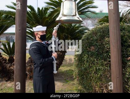 U.S. Navy Seemann S1C Jonathan Ruelos, dem Kommandanten zugewiesen, Flottenaktivitäten Sasebo läutet eine Glocke, um den zehnten Jahrestag des großen Tohoku-Erdbebens und Tsunami-Katastrophe 11. März 2021 in Sasebo, Japan, zu begehen. Das Erdbeben und der darauf folgende Tsunami führten in 20 japanischen Präfekturen zu 15.884 Todesfällen. Stockfoto