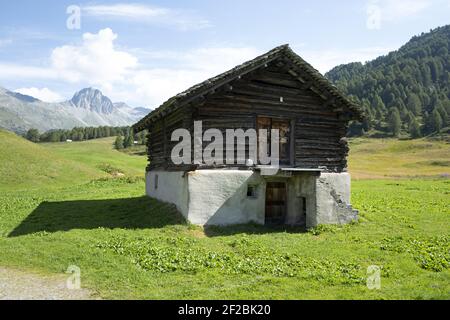 Berghütte mit Bergsee im Hintergrund, mit Panoramablick auf das Engadiner Tal, in der Schweiz. Stockfoto