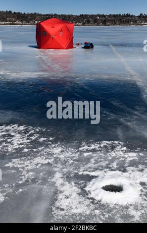 Rotes Eis-Angelzelt mit altem Eisloch auf gefroren Blaues Eis der Kempenfelt Bay am Simcoe See im Winter Stockfoto