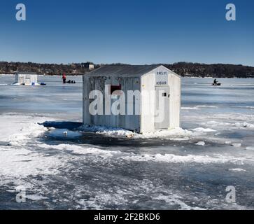 Eisangeln Hütten auf gefrorenen Kempenfelt Bay of Lake Simcoe Im Winter mit Fischern Angeln und Schleppen eines Schlittens Stockfoto