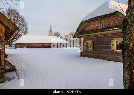 Altes Dorf Holzhäuser und Schuppen auf einem verschneiten Hang Stockfoto