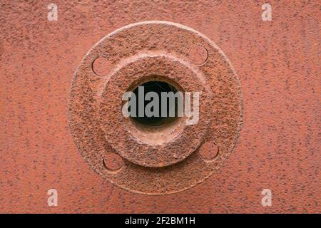 Das rostige Element des alten Baulochs ist mit Spinnweben überwuchert. Das Ersatzteil. Runde Eisenscheibe mit Schraubschnitten. Stockfoto