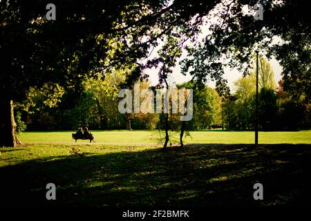 Freunde sitzen während der Covid-19-Sperre im Wandsworth Common, London, auf der Bank Stockfoto