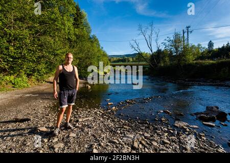 Schöner junger Mann am Fluss in Wetlina, polnisch Bieszczady Berge im Sommer. Stockfoto