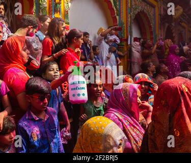 Anhänger feiern Holi im Dwarkadheesh Tempel. Die Teilnehmer tanzen, sprühen sich farbiges Wasser an und werfen sich farbiges Pulver an. Stockfoto