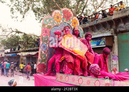 Indien, Mathura - Kinder auf einem Schwimmer rot gemalt Werfen farbige Pulver und Sprühen farbigen Wasser in der Holi Prozession in Mathura. Stockfoto