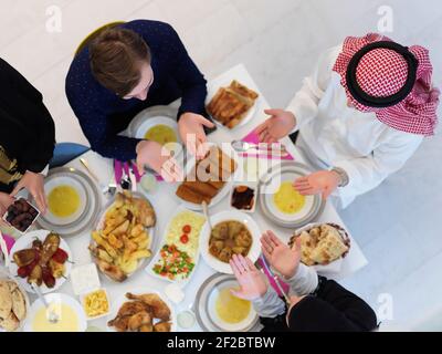 Draufsicht auf muslimische Familie, die während des Ramadan iftar dua zum Fastenbrechen macht. Araber halten die Hände in der Geste für das Gebet und Dank an Allah Stockfoto