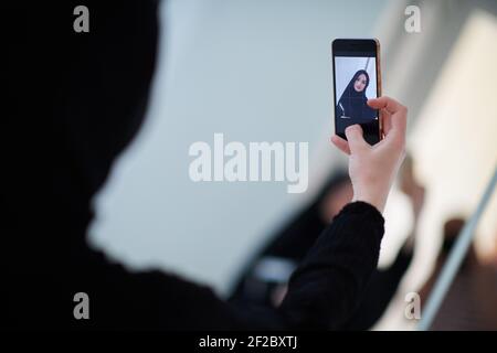 Junge muslimische Geschäftsfrau in traditioneller Kleidung oder Abaya beim Selfie. Stockfoto