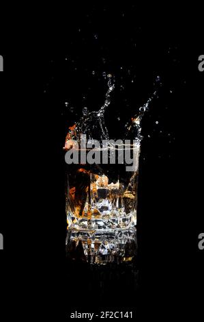 Glas Whiskey mit Spritzer, isoliert auf schwarzem Hintergrund. Alkoholisches Getränk mit Spritzer. Stockfoto