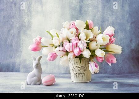 Osterdekoration und Tulpenstrauß in einer Vase auf blauem Hintergrund. Osterkonzept. Platz für Text kopieren Stockfoto