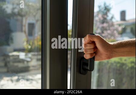 Kippen und drehen graue Farbe Aluminium-Fenster, Mann hält den Griff, frische Luft für zu Hause. Männliche Hand vertikal offenes Metall- oder PVC-Fenster, Nahaufnahme. Stockfoto
