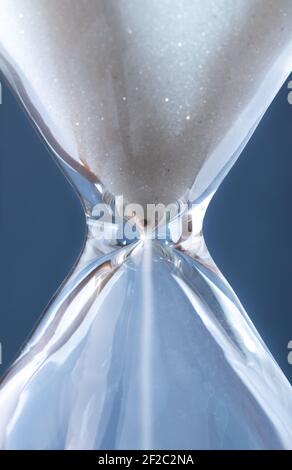 Sanduhr mit weißem Sand vor blauem Hintergrund Stockfoto