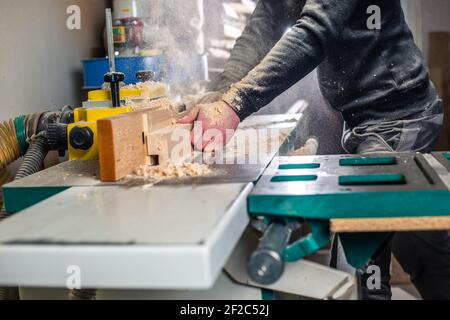 Professioneller Zimmermann, der das Holz auf der riesigen Säge schneidet, für ein modernes Möbel-, Schreinerei- und Holzwerkkonzept Stockfoto