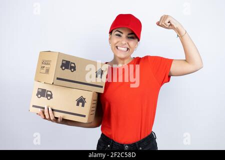 Junge schöne Frau trägt Kurier Uniform halten Lieferpakete sehr glücklich und aufgeregt machen Sieger Geste mit erhobenen Armen, lächelnd und SCR Stockfoto