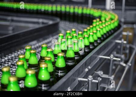 Automatisierte Förderlinie in einer Brauerei. Reihen von grünen Glasflaschen auf dem Förderer in Nahaufnahme. Industriebrauerei Stockfoto