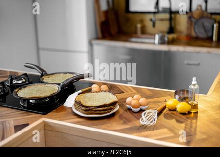 Zubereitung von Pfannkuchen zum Frühstück, Zutaten und gebratene Pfannkuchen auf dem Holztisch in der Küche zu Hause Stockfoto