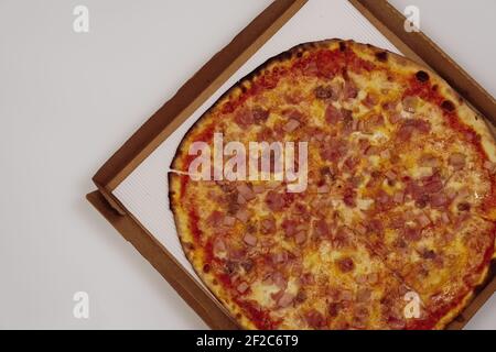 Pizza auf einem Karton Draufsicht, vor weißem Hintergrund. Nahaufnahme von tiefem Gericht traditionelle italienische Stil Lebensmittel Lieferung. Stockfoto