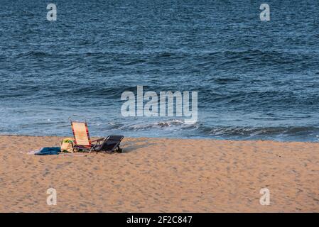 Ein Foto von Liegestühlen an einem leeren Spring Lake Strand, aufgenommen im weichen Licht einer frühen Morgensonne. Stockfoto