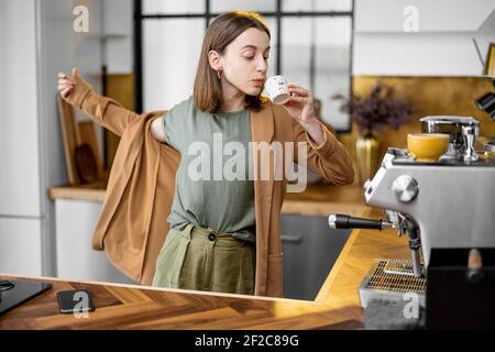 Pingelige junge Geschäftsfrau in Eile, um am Morgen zu arbeiten, tragen Jacke, trinken Kaffee und plaudern am Telefon unterwegs Stockfoto