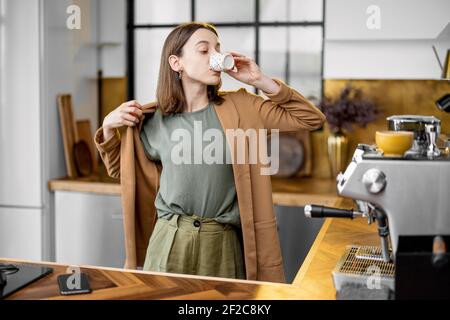 Pingelige junge Geschäftsfrau in Eile, um am Morgen zu arbeiten, tragen Jacke, trinken Kaffee und plaudern am Telefon unterwegs Stockfoto