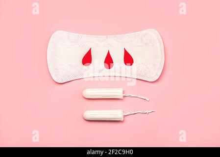 Menstruelle Damenbinden oder Servietten mit Papierbluttropfen auf Rosa Hintergrund.Weibliche intime gynäkologische Hygiene Konzept Stockfoto