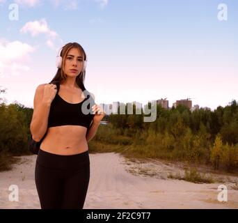 Junge sportliche Frau in Kopfhörer und einen Rucksack im Freien in Die Landschaft Stockfoto
