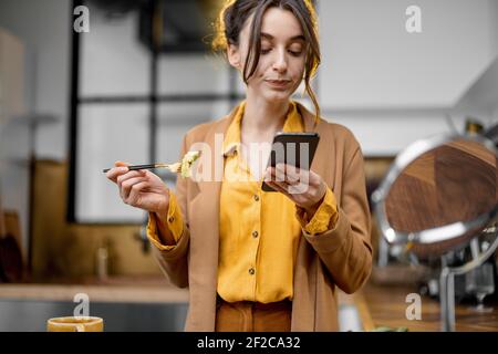 Pingelige junge Geschäftsfrau in Eile, um am Morgen zu arbeiten, Kaffee zu trinken, am Telefon zu plaudern und unterwegs Make-up zu finden Stockfoto