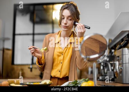 Pingelige junge Geschäftsfrau in Eile, um am Morgen zu arbeiten, Frühstück zu essen und sich unterwegs schminken Stockfoto