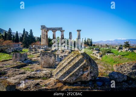 Korinth Griechenland Tempel von Apollo mit schneebedeckten Bergen in der Abstand und Abgrund der gefallenen Säulen im Vordergrund Stockfoto