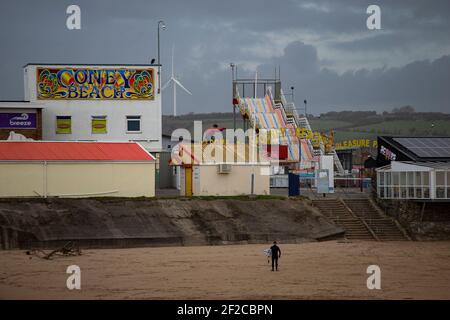 Ein Surfer am Coney Beach, Porthcawl bei Flut und starken Winden von 67mph trifft die South Wales Coast am 11th. März 2021. Kredit: Lewis Mitc Stockfoto