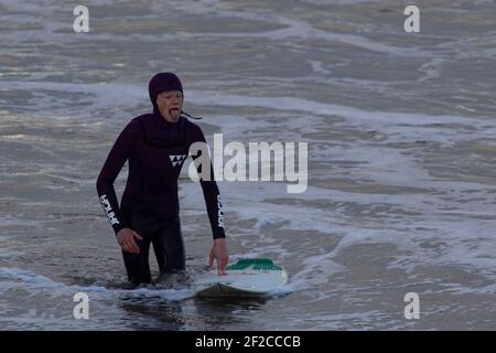 Ein Surfer am Coney Beach, Porthcawl bei Flut und starken Winden von 67mph trifft die South Wales Coast am 11th. März 2021. Kredit: Lewis Mitc Stockfoto