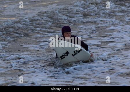 Ein Surfer am Coney Beach, Porthcawl bei Flut und starken Winden von 67mph trifft die South Wales Coast am 11th. März 2021. Kredit: Lewis Mitc Stockfoto