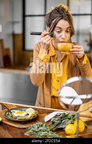 Pingelige junge Geschäftsfrau in Eile, um am Morgen zu arbeiten, trinken Kaffee und aplying Make-up auf dem Weg Stockfoto