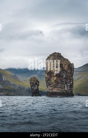 Nahaufnahme der berühmten Drangarnitr Klippe mit den Tindholmur Inseln in Der Hintergrund wurde während der morgendlichen Wanderung im Frühjahr aufgenommen Färöische Küste Stockfoto