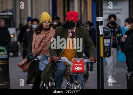 Männer und Frauen, die während der Coronavirus-Pandemie auf „Boris Bikes“ entlang der Oxford Street mit Facemarks unterwegs waren, London, England, Großbritannien Stockfoto