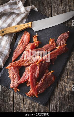 Getrocknetes Hühnerfleisch. Leckeres, ruckiges Fleisch auf Schneidebrett. Draufsicht. Stockfoto