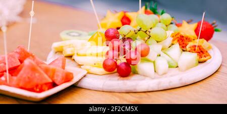 Platte Mit Frischem Obst. Rohe Bio-Obstteller Mit Beeren, Melonen, Kiwi, Mango, Ananas, Wassermelone, Kaktuskerne, Karambola, Erdbeere Auf Dem Holzbrett, Auf Dem Tisch, Selektiver Fokus. Banner. Stockfoto