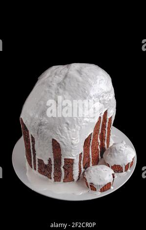 Hausgemachte handgemachte Osterkuchen, bedeckt mit weißer Glasur, auf einem Teller auf einem dunklen Hintergrund, isoliert Stockfoto