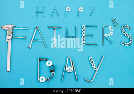 Text Happy Father's Day mit Schrauben, Muttern, Schraubenschlüssel und anderen Bauwerkzeugen auf blauem Hintergrund ausgekleidet. Flach liegend. Draufsicht Stockfoto