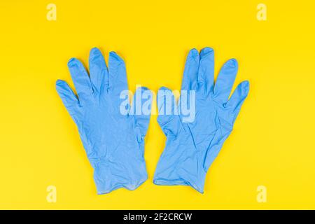 Ein Paar blaue Latexhandschuhe auf einer gelben Oberfläche Stockfoto