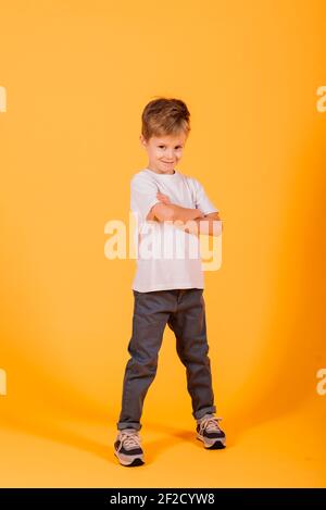 Portrait von glücklichen kleinen Jungen auf gelbem Hintergrund im Studio Stockfoto