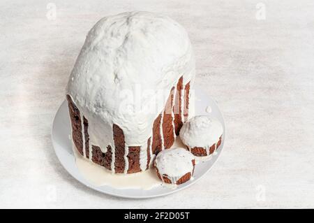 Hausgemachte handgemachte Osterkuchen, bedeckt mit weißer Glasur, auf einem Teller auf weißem Hintergrund. Stockfoto