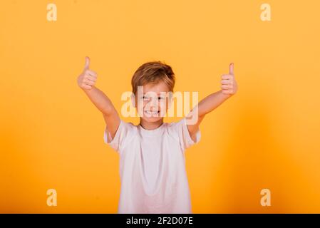 Portrait von glücklichen kleinen Jungen auf gelbem Hintergrund im Studio Stockfoto