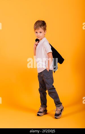 Portrait von glücklichen kleinen Jungen auf gelbem Hintergrund im Studio Stockfoto