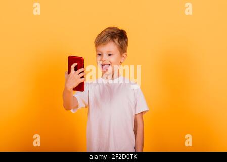 Portrait von glücklichen kleinen Jungen auf gelbem Hintergrund im Studio Stockfoto